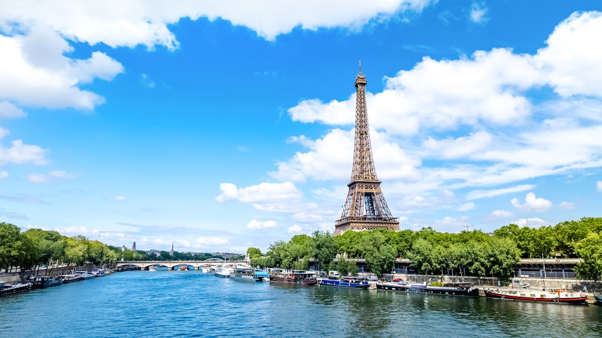 Eiffel Tower beside the Seine River in Paris with boats along the riverbank.