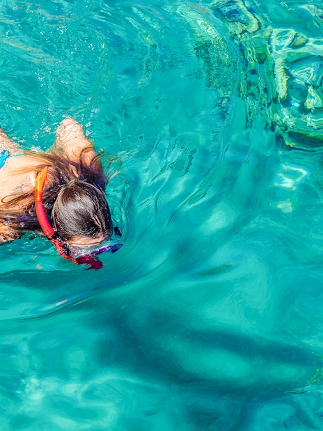 Teenage girl snorkeling in clear blue water.