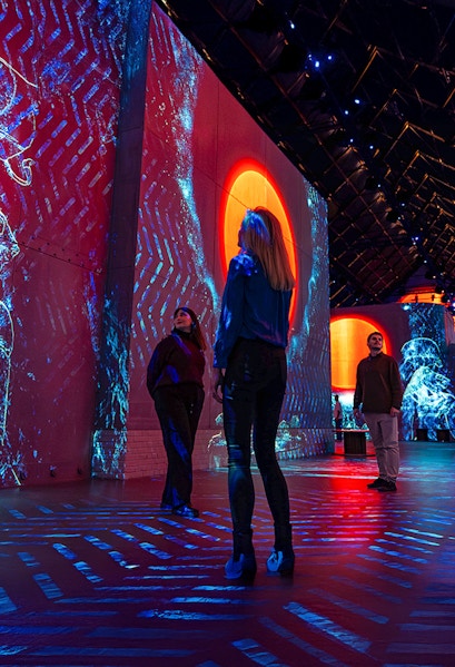 Visitors exploring immersive digital art projections at Fabrique des Lumières.