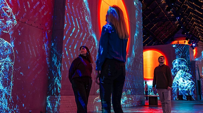 Visitors exploring immersive digital art projections at Fabrique des Lumières.