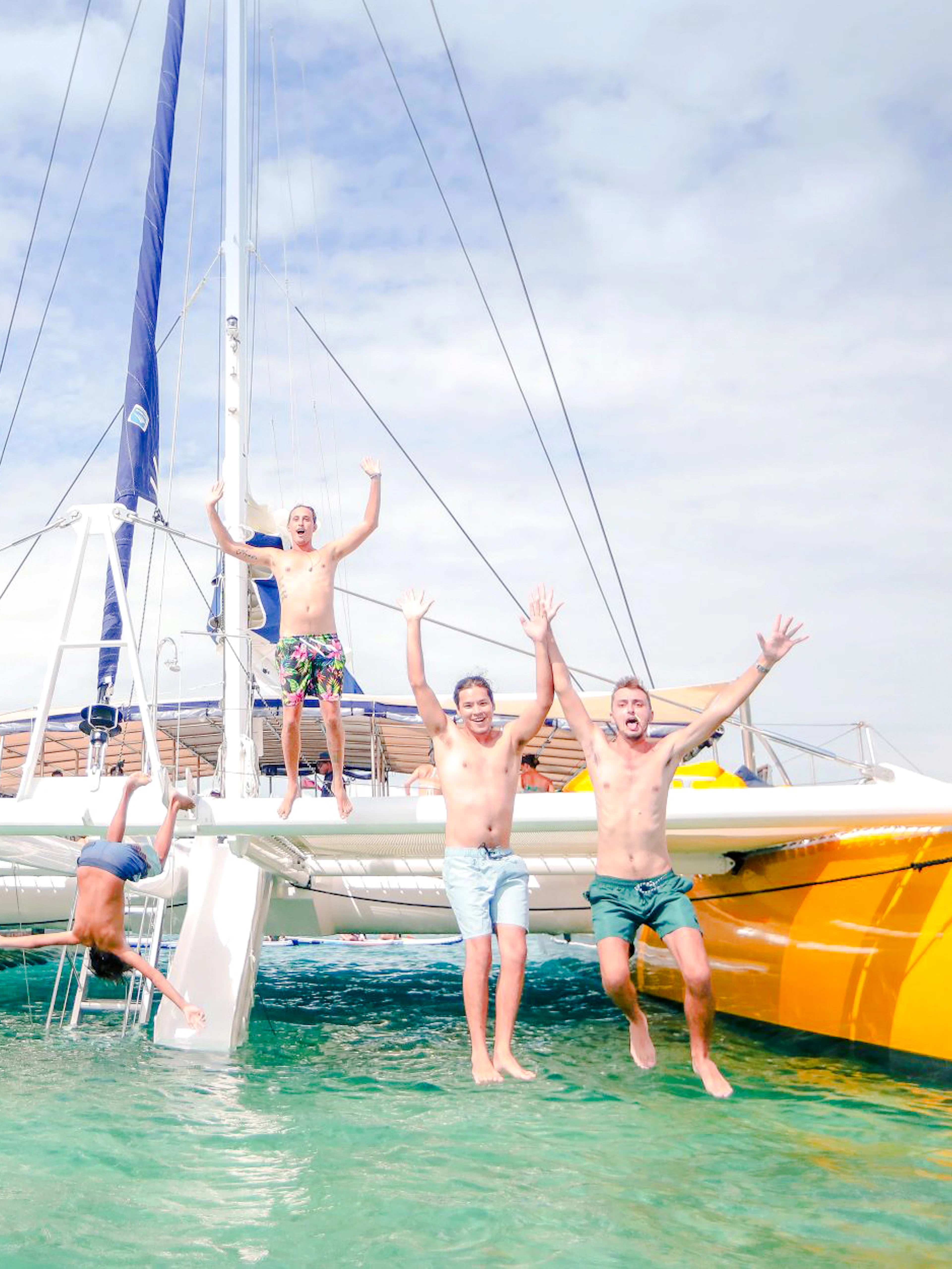 People jumping off a catamaran during South Sea Sailing in Fiji.