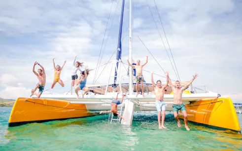 People jumping off a catamaran during South Sea Sailing in Fiji.