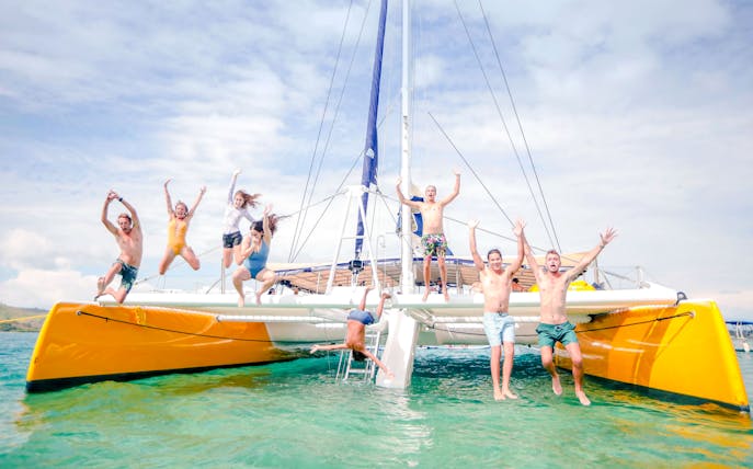 People jumping off a catamaran during South Sea Sailing in Fiji.