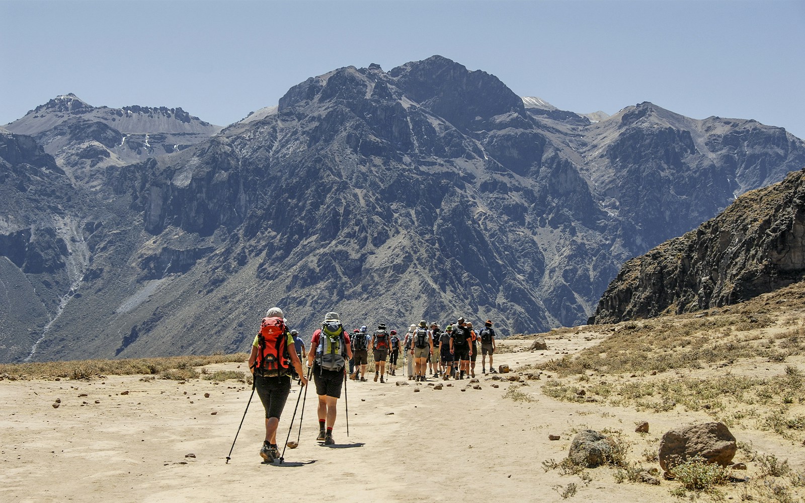 Tour group exploring the breathtaking Colca Canyon, Peru, with a local guide pointing out unique features