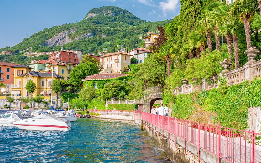 Colorful buildings and boats along Lake Como shoreline, Italy.