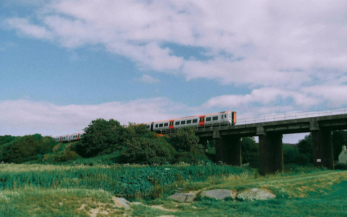 Train crossing a bridge in a lush European countryside.