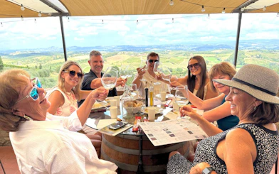Group enjoying wine tasting at a Tuscan winery with scenic vineyard views.