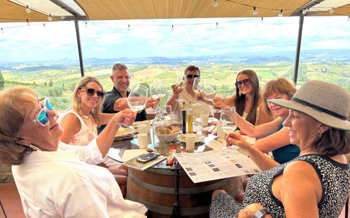 Group enjoying wine tasting at a Tuscan winery with scenic vineyard views.
