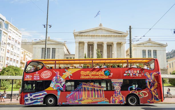 Open-top tour bus in front of the Vallianeio Megaron, Athens.