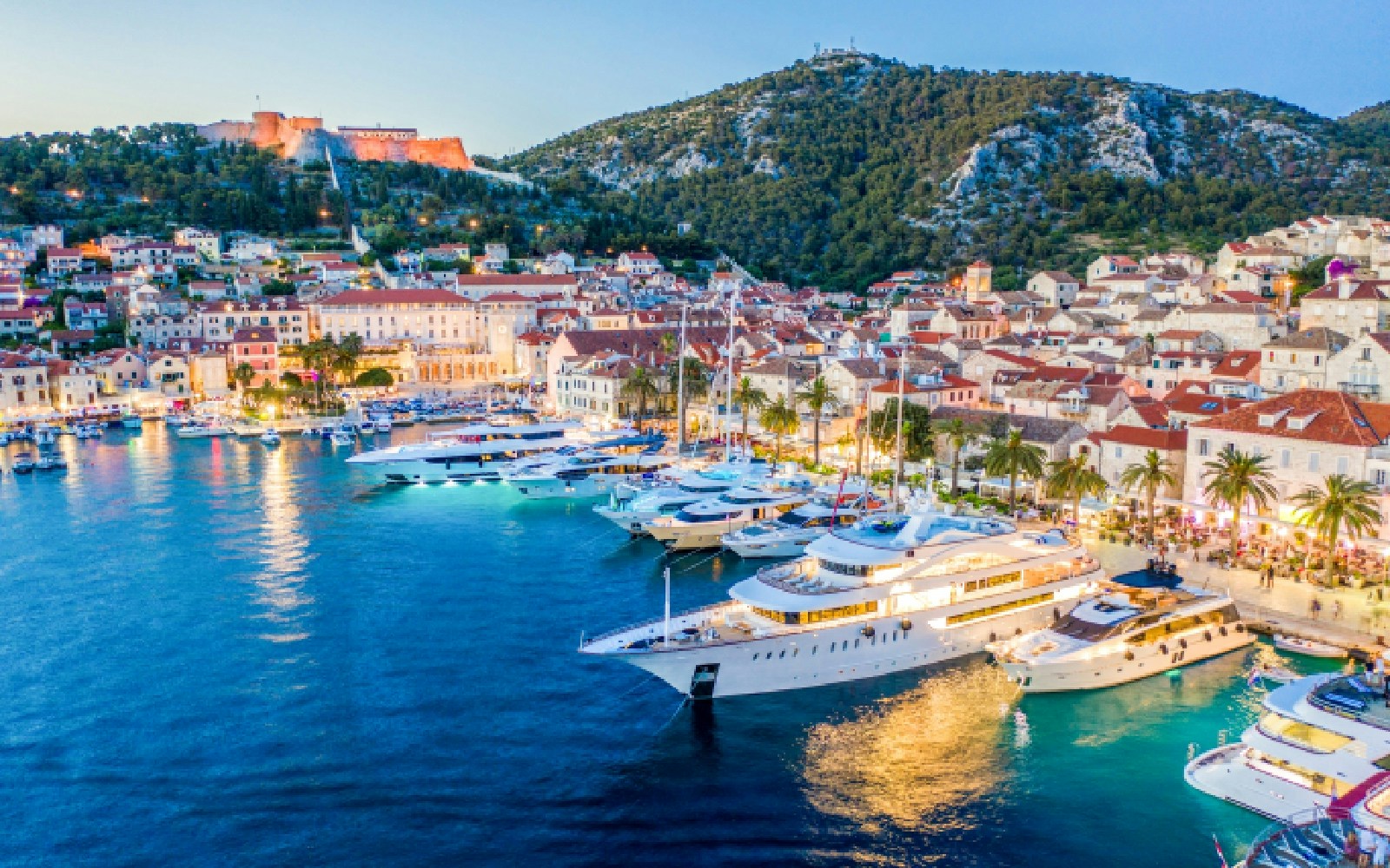 Yachts docked along the coast of Hvar, Croatia with historic buildings in the background.