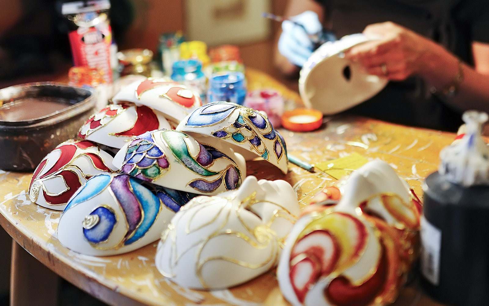 Venetian artisan crafting traditional mask in costume workshop, Venice, Italy.