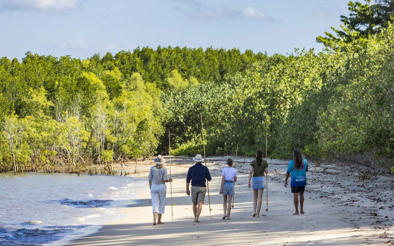 Group walking along a beach with fishing spears, Daintree Dreaming Tour, Australia.