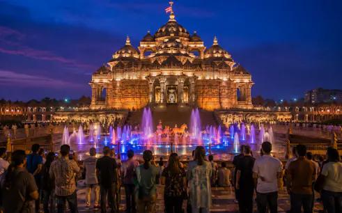 Visitors watching illuminated Akshardham Temple with fountains during evening, Agra spiritual tour.