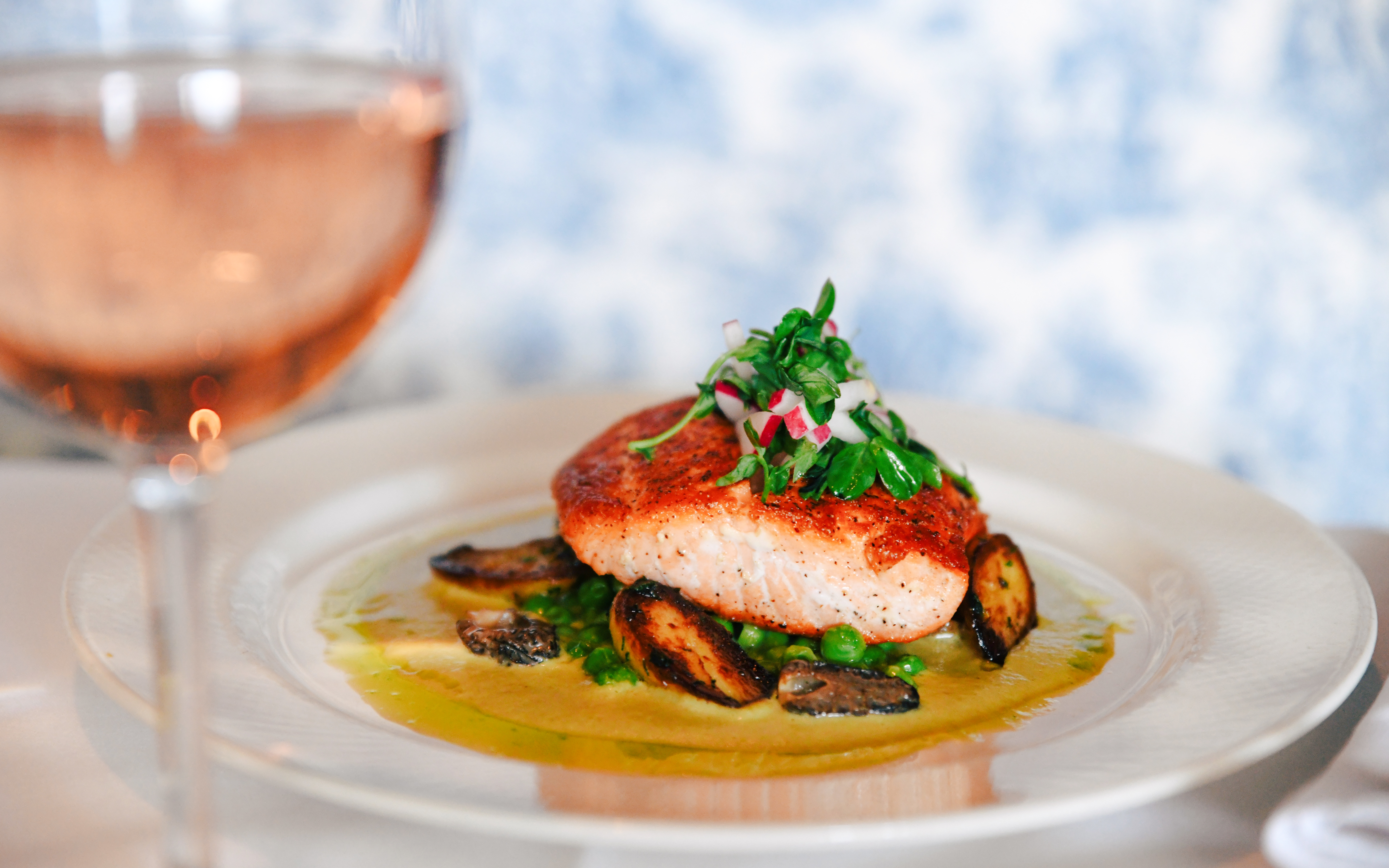 Salmon fillet with greens and mushrooms, French fine dining setting.
