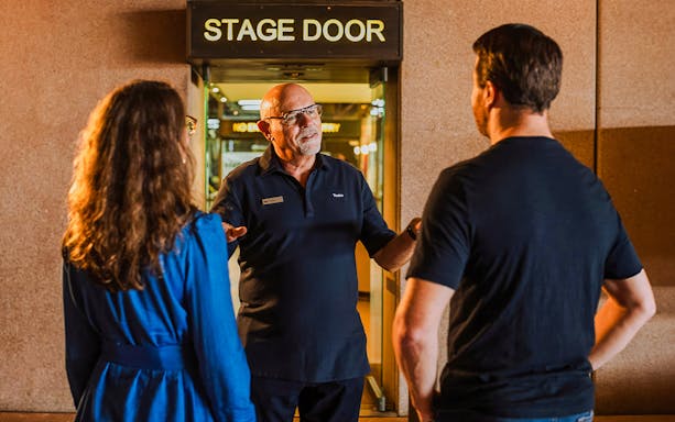 Backstage tour guide speaking to visitors at Sydney Opera House stage door.