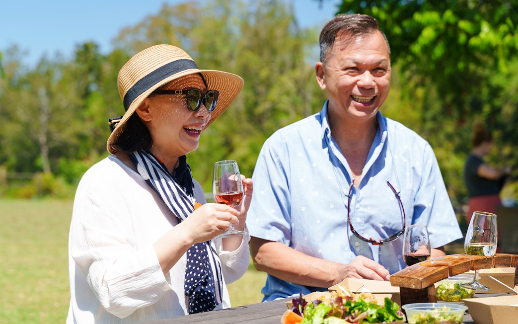 Couple enjoying wine tasting at O'Reilly's Vineyard, Lamington National Park tour.
