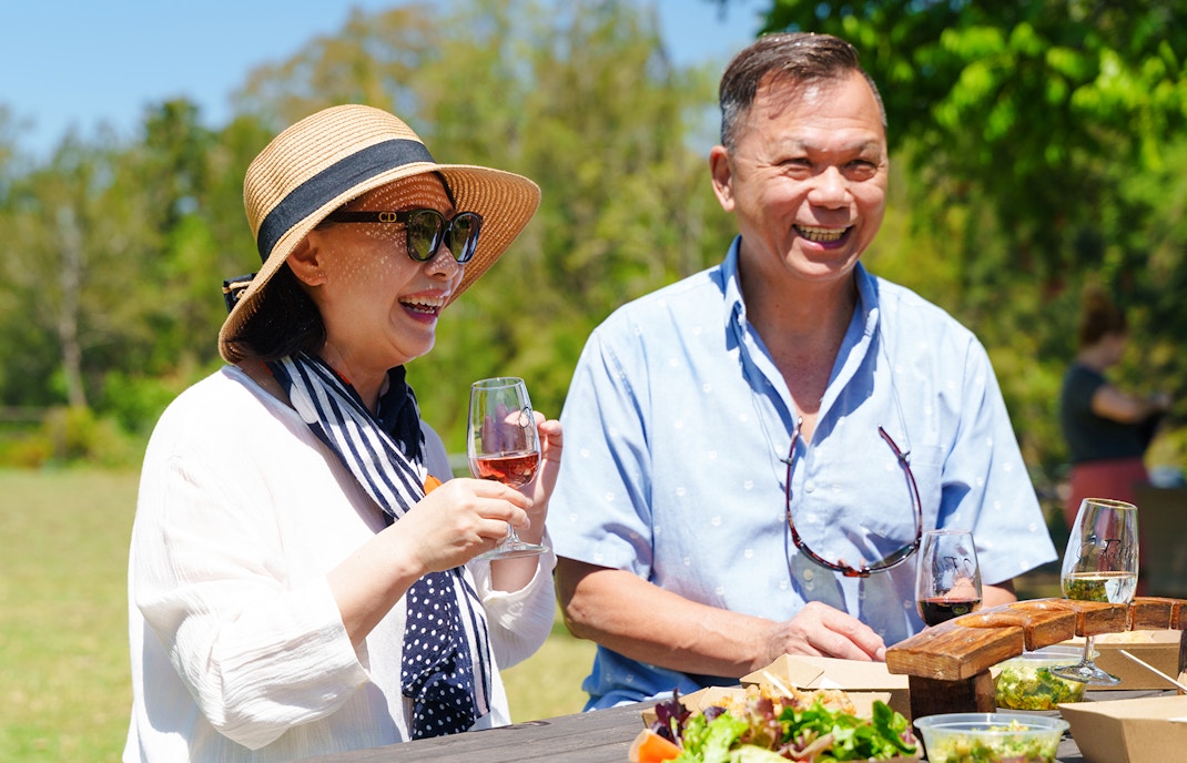 Couple enjoying wine tasting at O'Reilly's Vineyard, Lamington National Park tour.