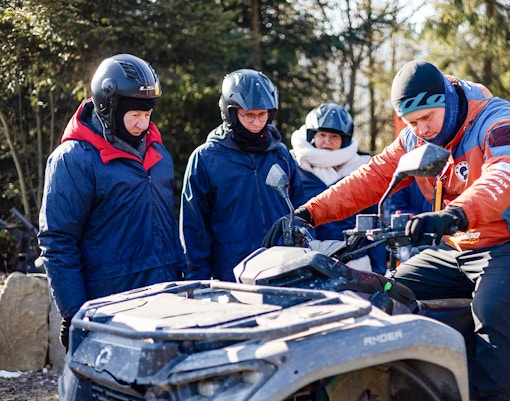 Group preparing for quad biking in Zakopane with guide explaining controls.