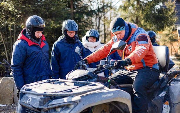 Group preparing for quad biking in Zakopane with guide explaining controls.