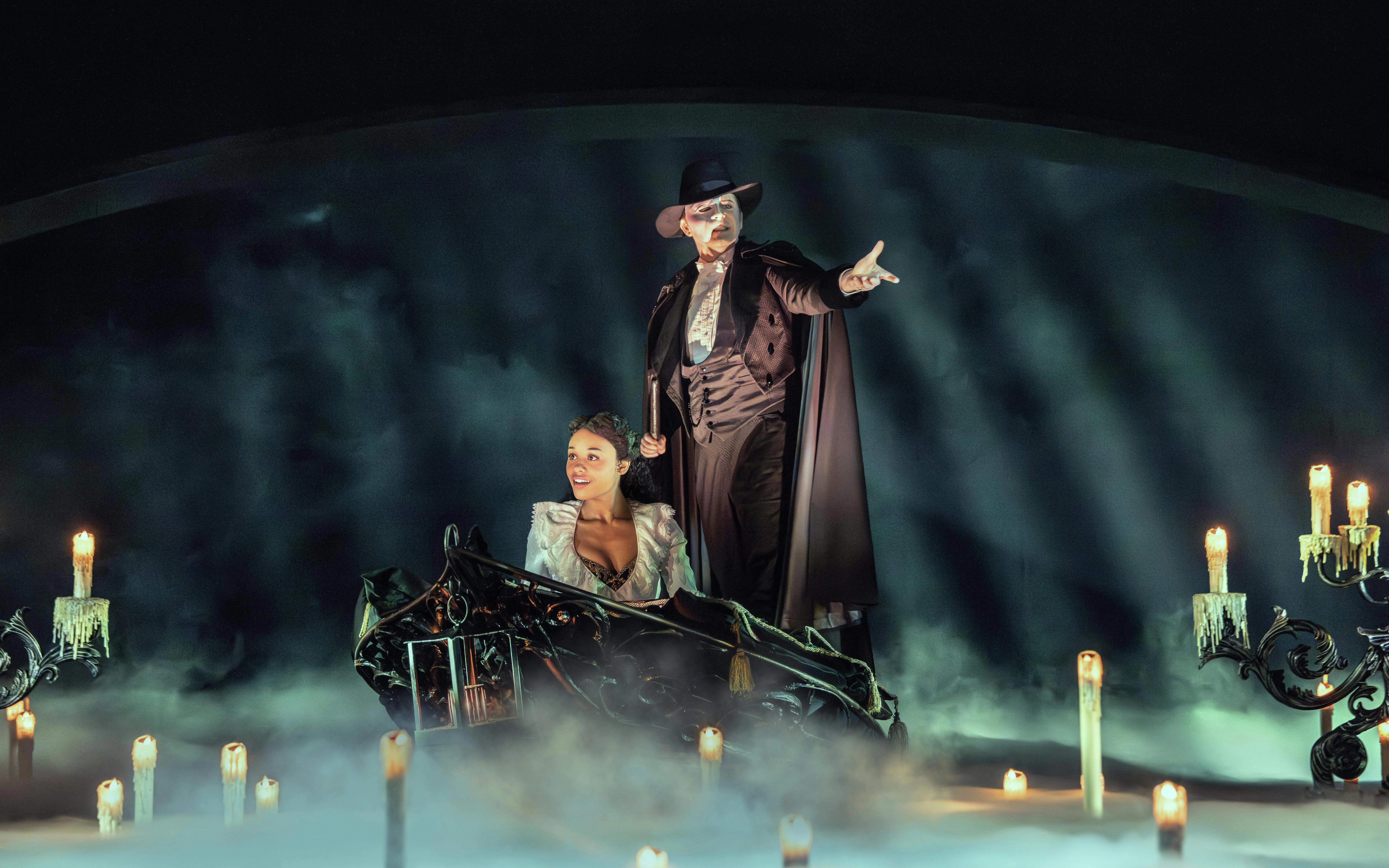 Phantom of the Opera scene with characters on a boat surrounded by candles and mist.