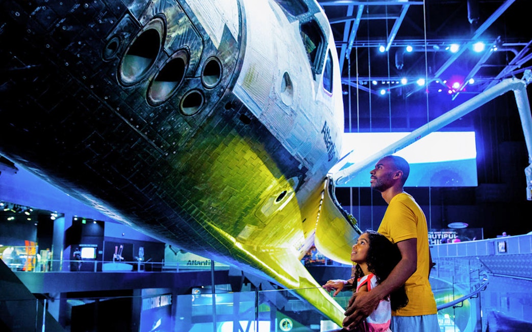 Family observing Atlantis Shuttle at Kennedy Space Center.