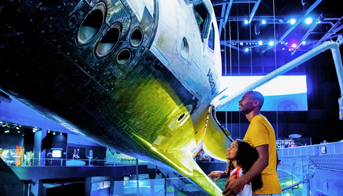 Family observing Atlantis Shuttle at Kennedy Space Center.