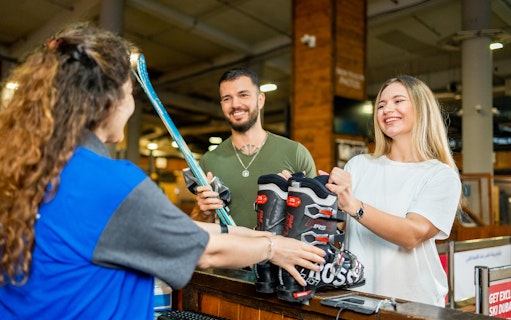 Customers receiving ski equipment at Ski Dubai rental counter.