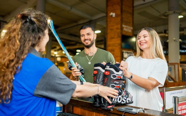 Customers receiving ski equipment at Ski Dubai rental counter.