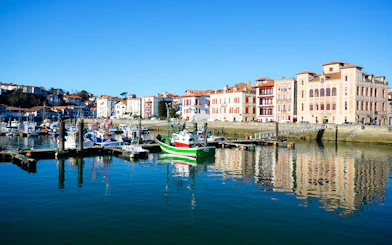 Harbor view with colorful boats and historic buildings in Basque Country, Spain.