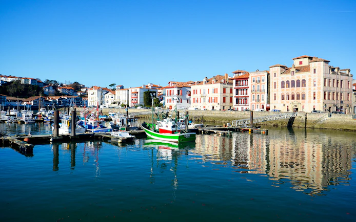 Harbor view with colorful boats and historic buildings in Basque Country, Spain.