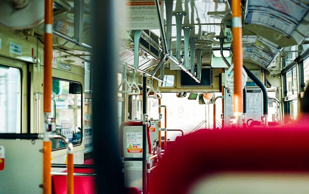 Interior of a highway bus in Japan, showing seats and handrails.