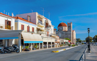 Street view of a small town on Aegina island with cafes and a church.