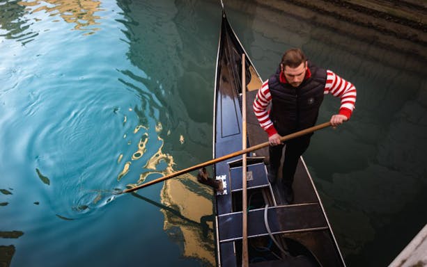 Gondolier rowing a gondola on a canal in Venice, Italy.