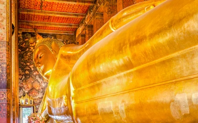 Reclining Buddha statue at Wat Pho, Bangkok, with intricate temple murals.