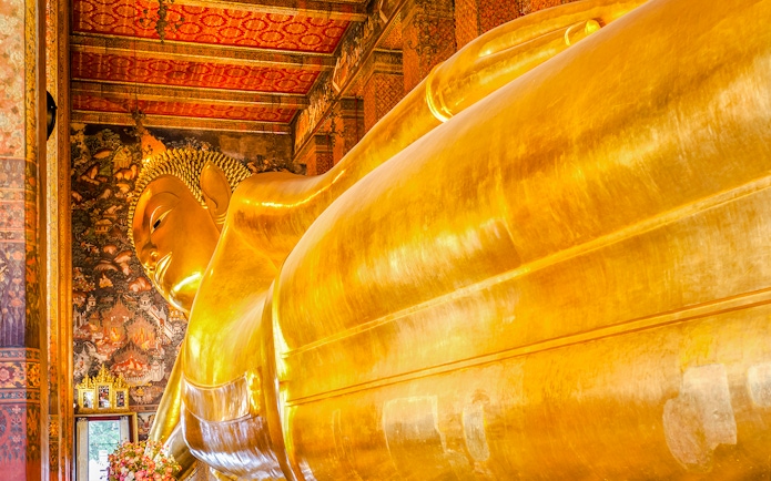 Reclining Buddha statue at Wat Pho, Bangkok, with intricate temple murals.