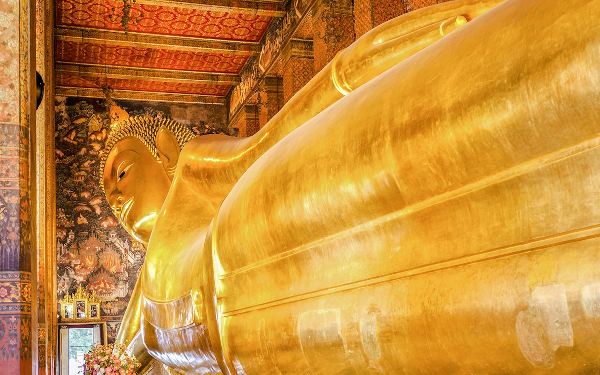 Reclining Buddha statue at Wat Pho, Bangkok, with intricate temple murals.