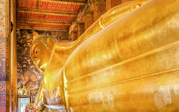 Reclining Buddha statue at Wat Pho, Bangkok, with intricate temple murals.