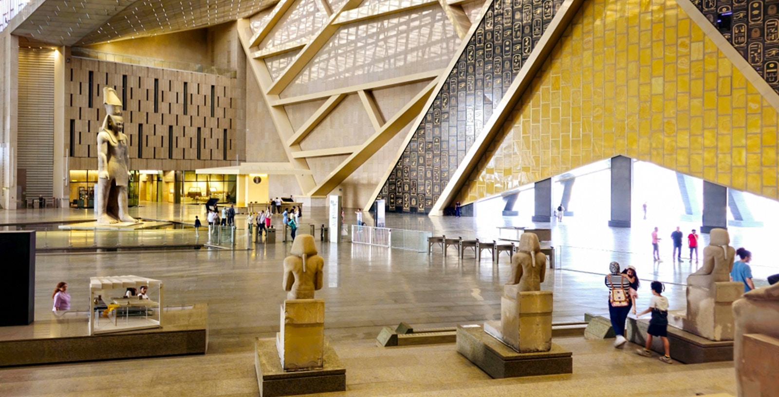 Grand Egyptian Museum interior with large statue and visitors exploring exhibits.