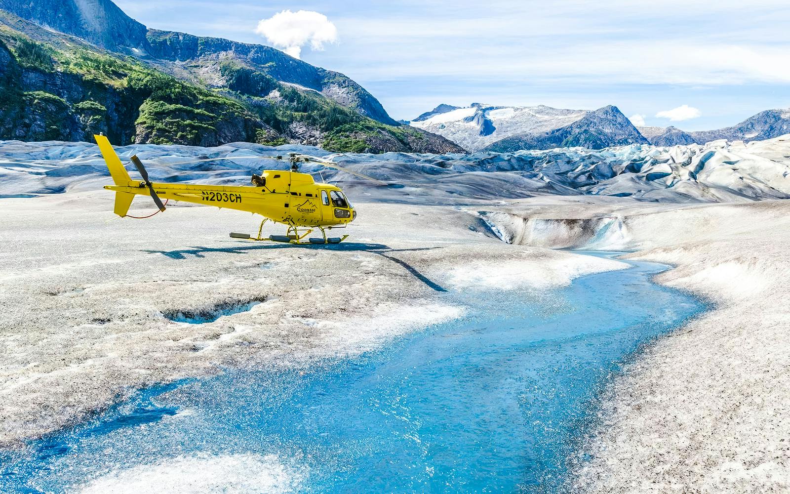 Yellow helicopter on a glacier with a blue stream in Juneau, Alaska.
