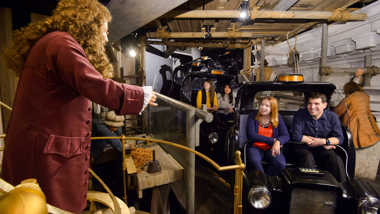 Visitors on a ride at Madame Tussauds London, featuring historical figures and scenes.