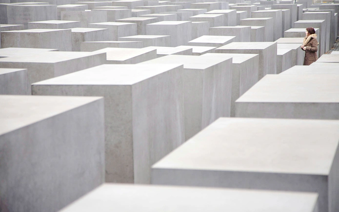 Visitor walking through concrete slabs at Holocaust Memorial, Berlin.