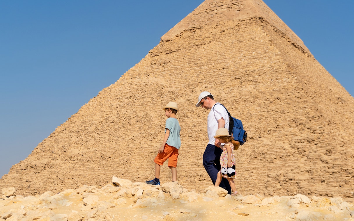 Father and children walking by the Chephren Pyramid on the Giza Plateau, Egypt.