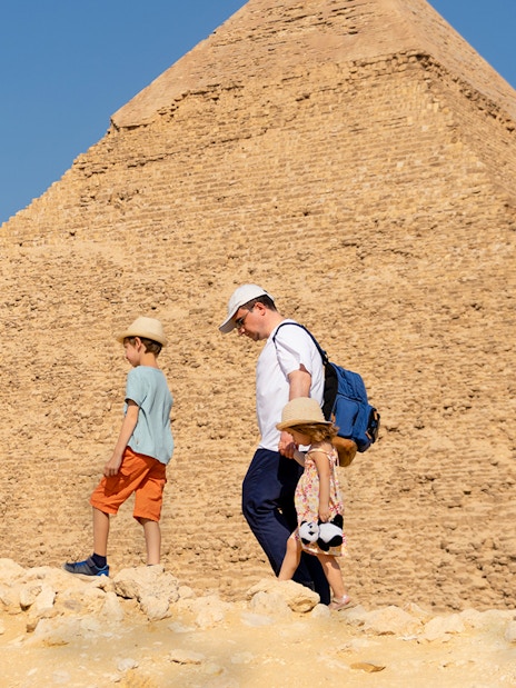 Father and children walking by the Chephren Pyramid on the Giza Plateau, Egypt.