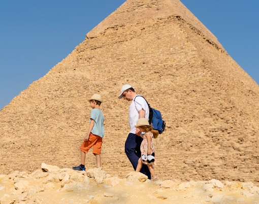 Father and children walking by the Chephren Pyramid on the Giza Plateau, Egypt.