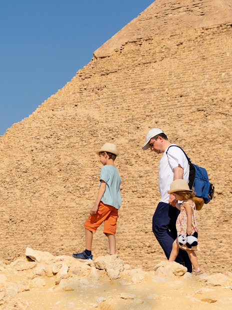 Father and children walking by the Chephren Pyramid on the Giza Plateau, Egypt.
