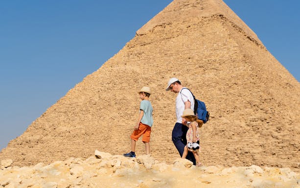 Father and children walking by the Chephren Pyramid on the Giza Plateau, Egypt.