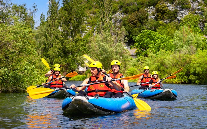 Canoe safari group paddling on a river near Split, surrounded by lush greenery.