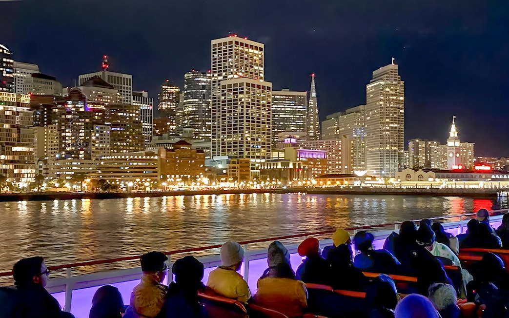 Guests on deck viewing San Francisco skyline during California sunset cruise.