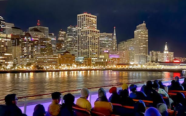 Guests on deck viewing San Francisco skyline during California sunset cruise.