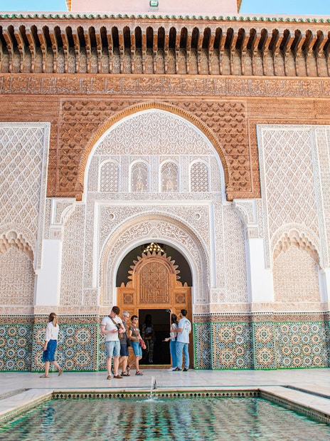 Ben Youssef Madrasa courtyard with intricate tilework and arches, Marrakech, Morocco.